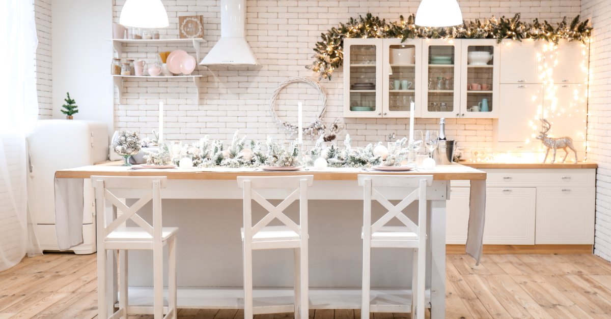 A kitchen with winter decorations. There are candles and greenery on the kitchen table with decor accents.