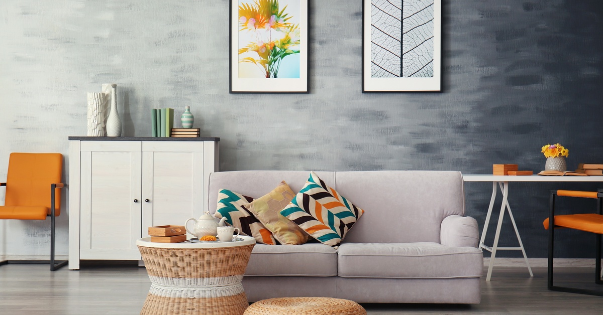  A room with a couch, a chair, a table, a cabinet, and two framed pieces of wall art. The accent colors are orange and blue.